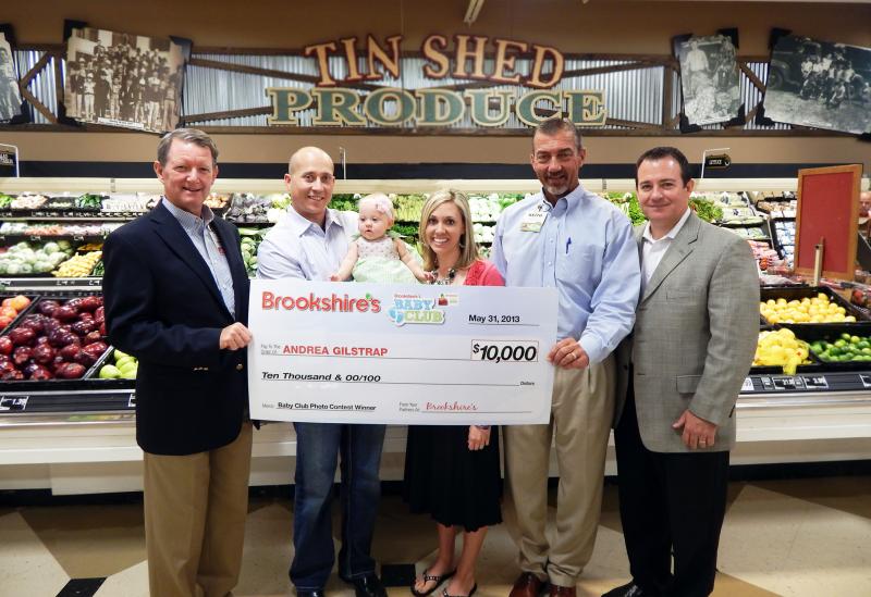 Rick Ellis (left), vice president of marketing for Brookshire Grocery Co., presents the chain's new spokesbaby with a check for $10,000.