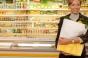Lady holding bagged groceries in front of dairy case.jpg