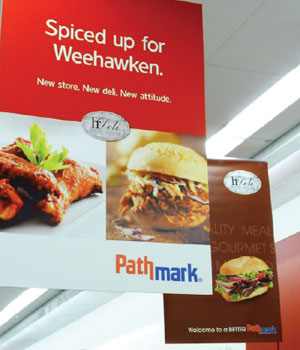 Weehawken store signs emphasize private-label perishables and reinforce a “local” feel.
